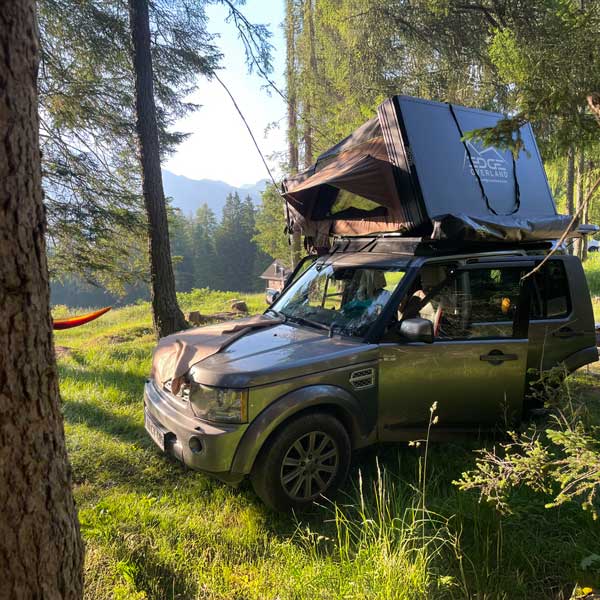 Sisa and Balint relaxing whilst rooftop tent camping in the middle of the woods
