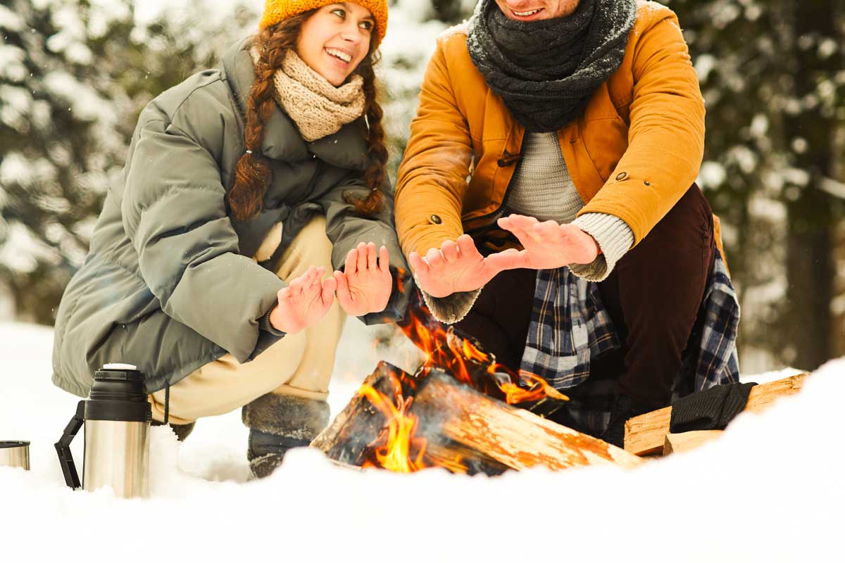 Couple warming themselves by a campfire