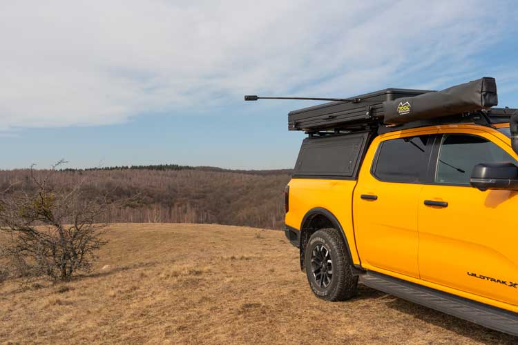El soporte de cámara para tienda de coche instalado en el lateral de la tienda con un polo de extensión y una cámara de acción.