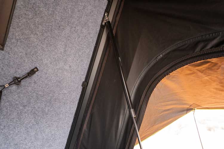 Rozsdamentes acél gázrugók fekete porfestéssel nyitják fel a tetősátor felső fedelét, miközben professzionális megjelenést biztosítanak belül.