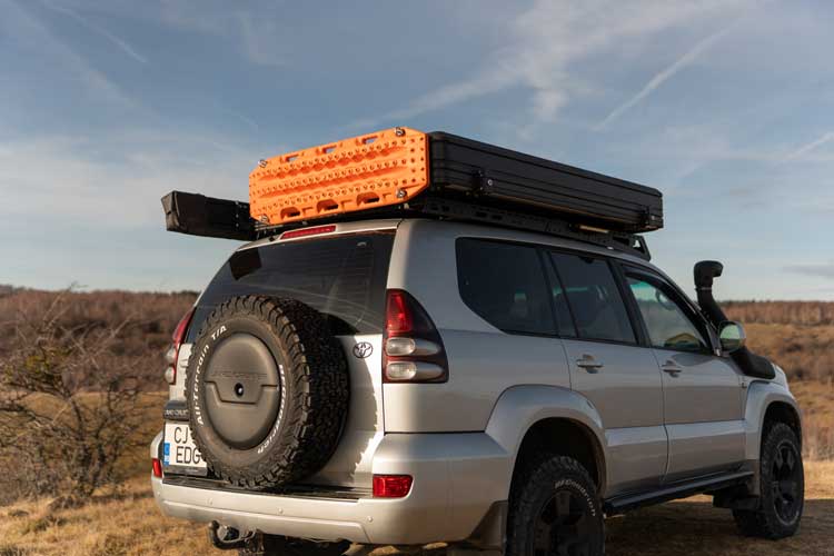 Vedere de ansamblu, de la distanță, a unui vehicul de overlanding echipat cu un cort de plafon Horizon, care transportă plăci de tracțiune pe cort datorită suporturilor dedicate.